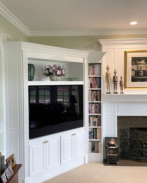 White painted built-in around a television and fireplace.