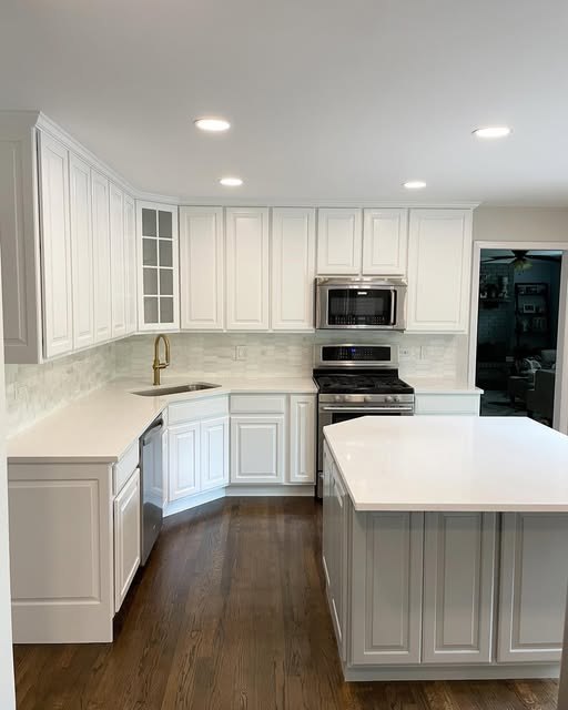 White kitchen David finished: painted cabinets, tile backsplash, and hardwood floor.