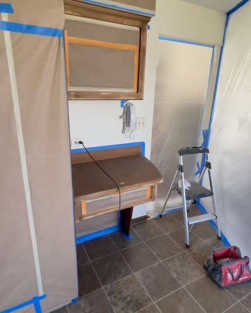 A room masked with plastic and painter’s tape before the walls are painted.